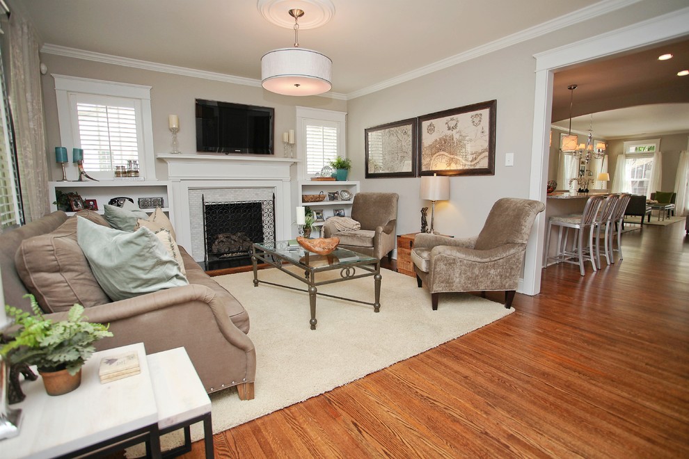 Example of a mid-sized arts and crafts medium tone wood floor family room design in Charlotte with gray walls and a standard fireplace