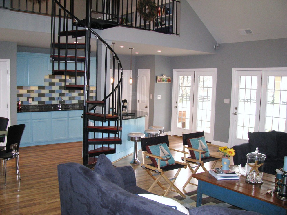 Imagen de sala de estar con barra de bar tipo loft de estilo de casa de campo de tamaño medio con paredes grises, suelo de madera clara y pared multimedia