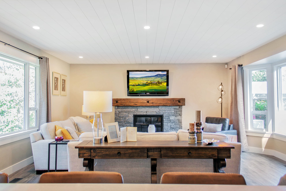 Cette photo montre une salle de séjour nature de taille moyenne et ouverte avec un mur beige, une cheminée standard, un manteau de cheminée en pierre, un téléviseur fixé au mur et un sol marron.
