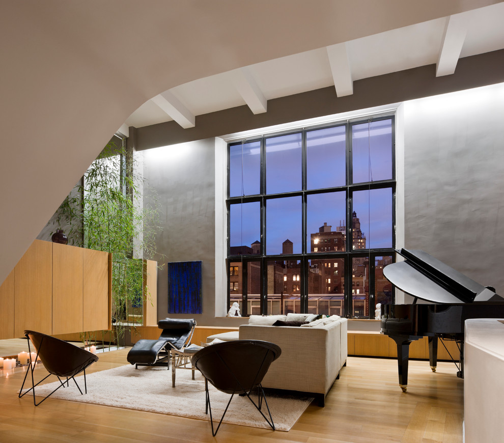 Cette photo montre une très grande salle de séjour tendance ouverte avec une salle de musique, un mur gris et un sol en bois brun.