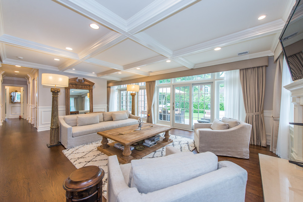 Example of a huge classic open concept medium tone wood floor family room design in New York with gray walls and a wall-mounted tv