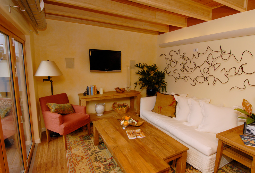 Idées déco pour une petite salle de séjour contemporaine fermée avec un mur jaune, un sol en bois brun et un téléviseur fixé au mur.