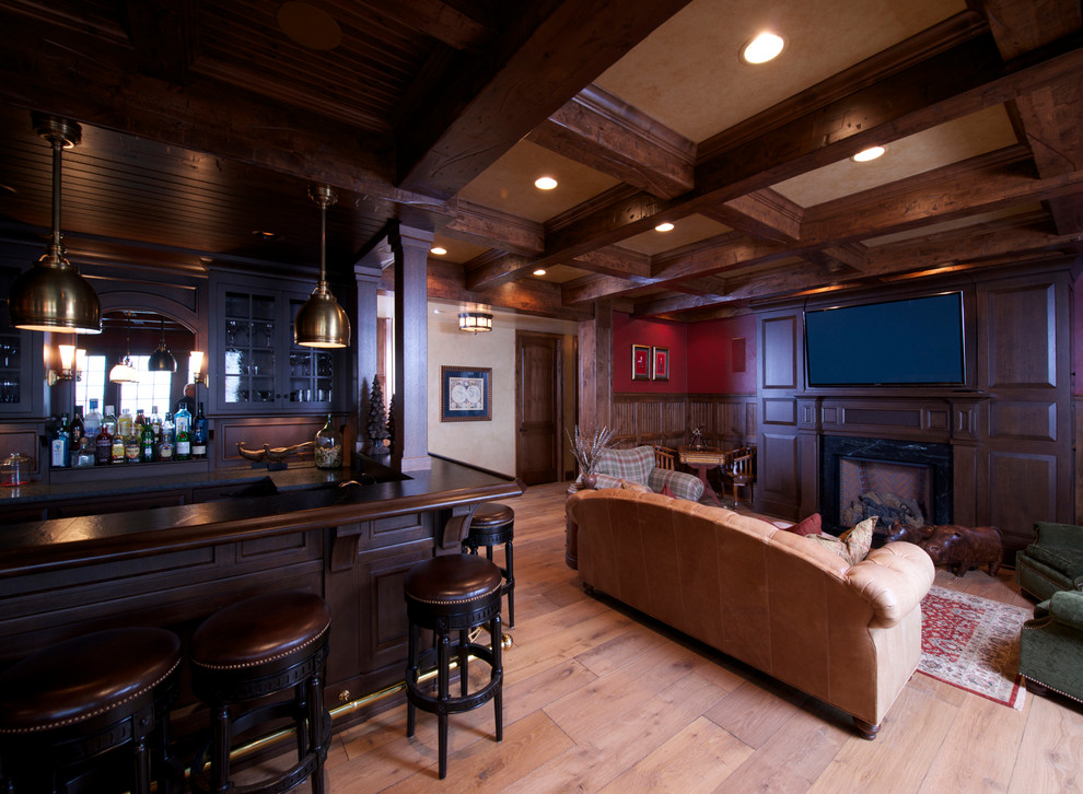 Modelo de sala de estar con barra de bar cerrada tradicional renovada grande con paredes marrones, suelo de madera clara, todas las chimeneas, marco de chimenea de madera y televisor colgado en la pared