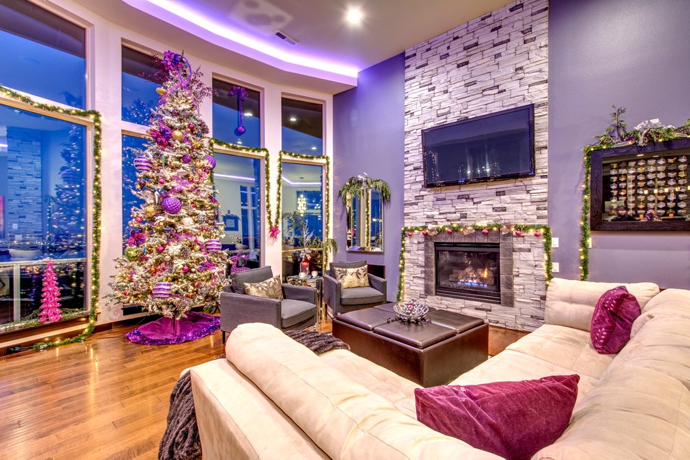 На фото: огромная открытая гостиная комната в современном стиле с фиолетовыми стенами, темным паркетным полом, стандартным камином, фасадом камина из камня и телевизором на стене