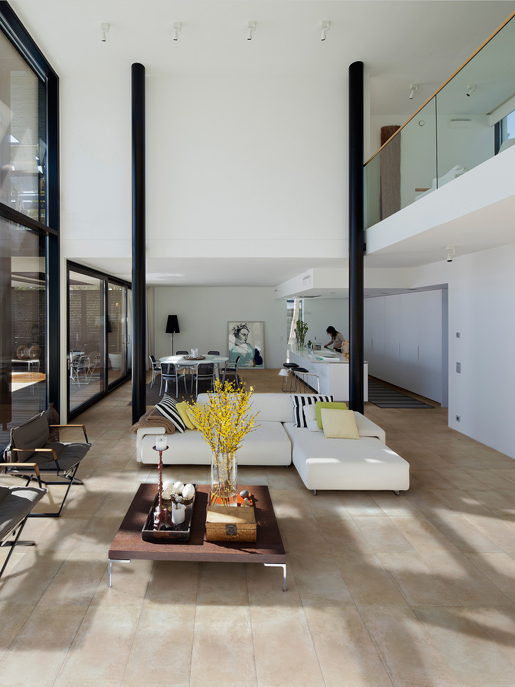На фото: большая двухуровневая гостиная комната в стиле модернизм с белыми стенами и полом из керамической плитки