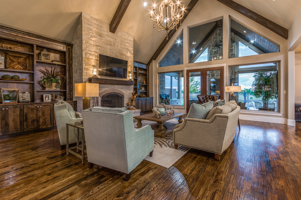 Family room - large rustic open concept dark wood floor family room idea in Dallas with beige walls, a standard fireplace, a stone fireplace and a wall-mounted tv