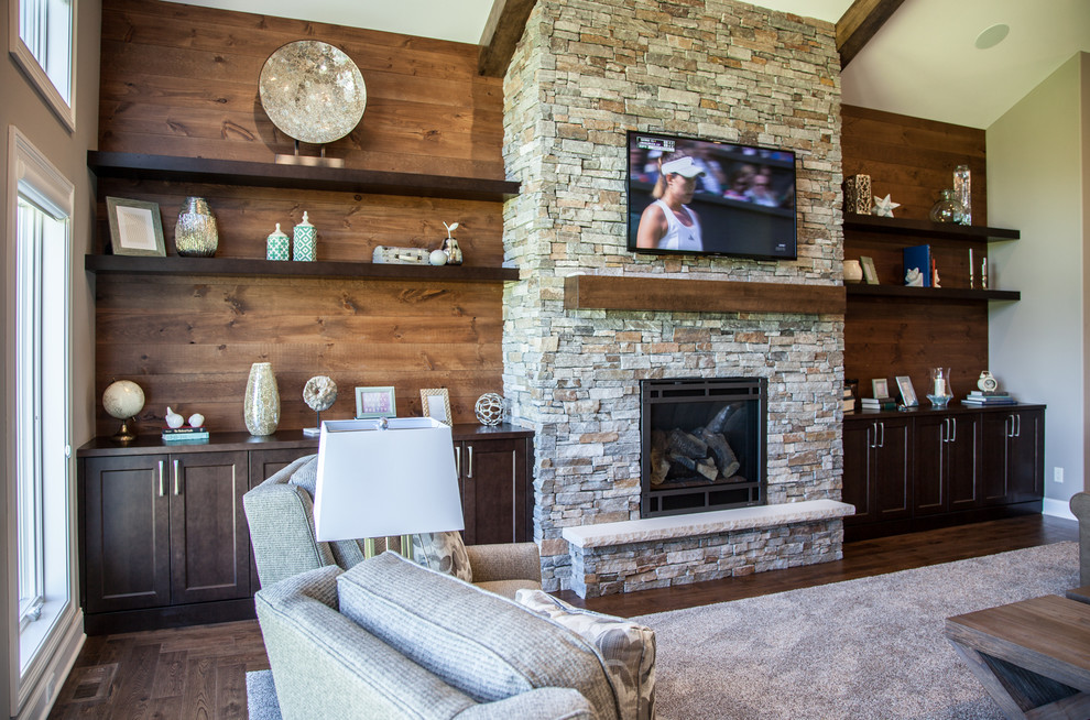 Cette image montre une salle de séjour traditionnelle avec un mur beige, parquet foncé, une cheminée standard, un manteau de cheminée en pierre, un téléviseur fixé au mur et un sol marron.
