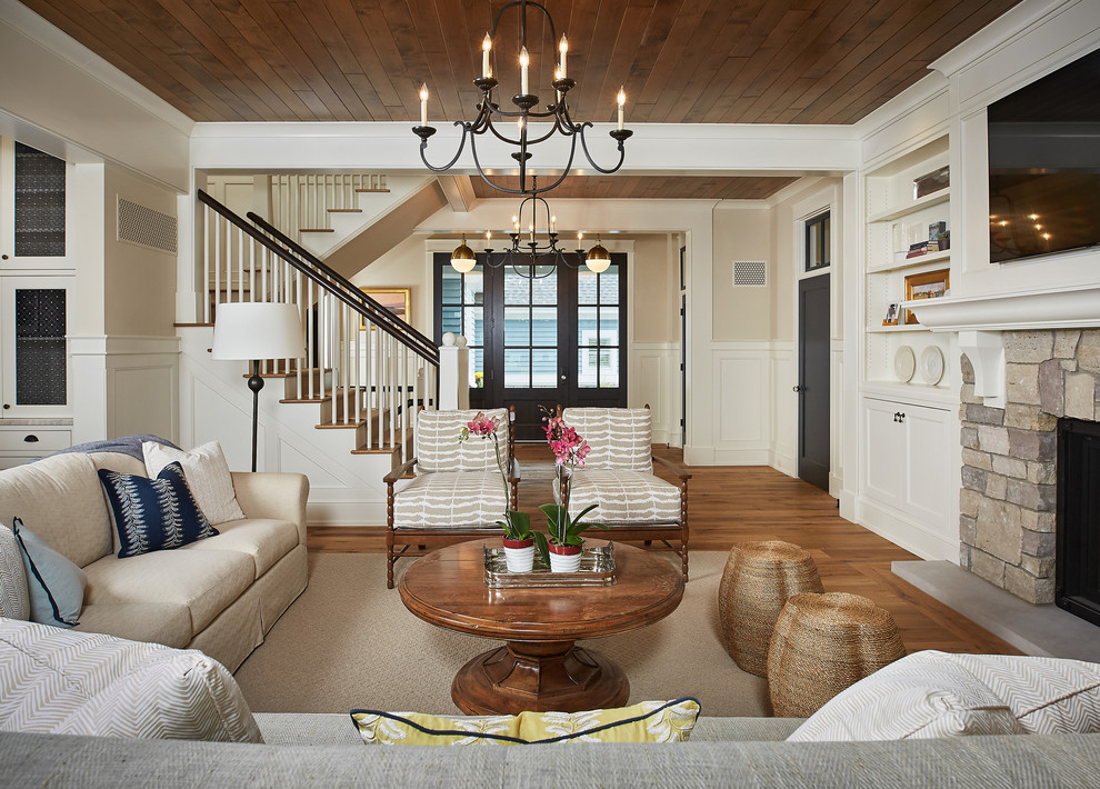 Mid-sized beach style open concept medium tone wood floor family room photo with a standard fireplace, a stone fireplace, a wall-mounted tv and beige walls