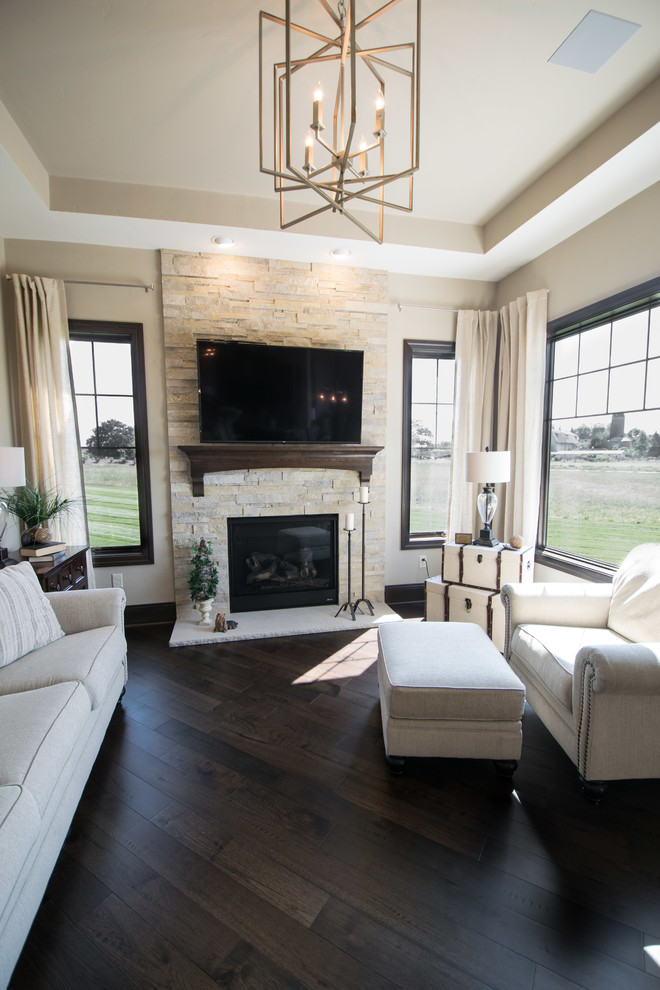 Example of a mid-sized transitional open concept dark wood floor and brown floor family room design in Milwaukee with beige walls, a standard fireplace, a stone fireplace and a wall-mounted tv