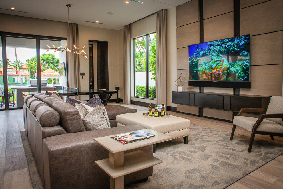 Moderner Hobbyraum ohne Kamin mit beiger Wandfarbe, braunem Holzboden und TV-Wand in Miami