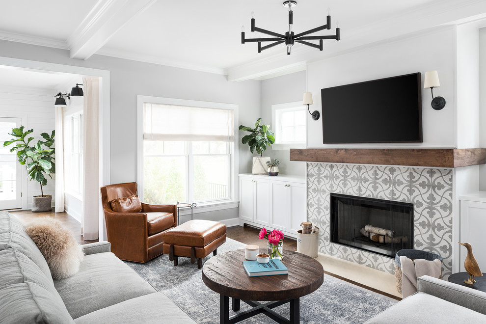 Offenes Landhausstil Wohnzimmer mit grauer Wandfarbe, braunem Holzboden, Kamin, gefliester Kaminumrandung, TV-Wand und braunem Boden in Chicago