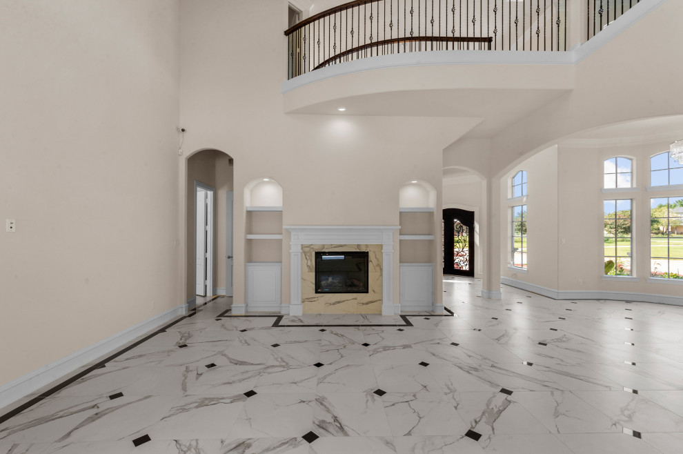Large mediterranean open plan games room in Dallas with white walls, porcelain flooring, a standard fireplace, a tiled fireplace surround, a wall mounted tv, white floors and a vaulted ceiling.