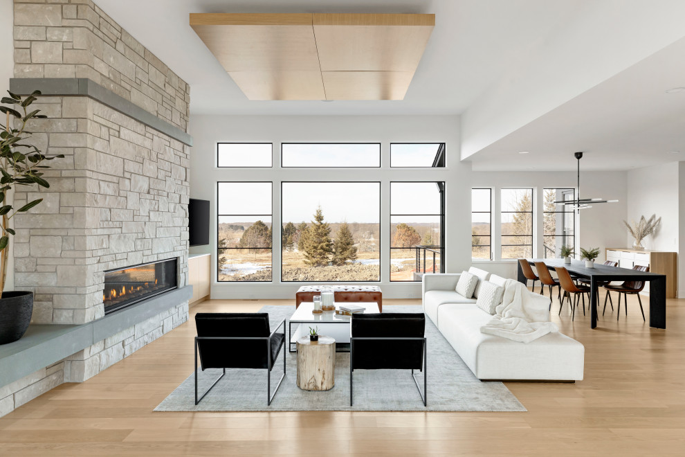 Foto de sala de estar abierta contemporánea con suelo de madera clara, todas las chimeneas, marco de chimenea de piedra y suelo marrón