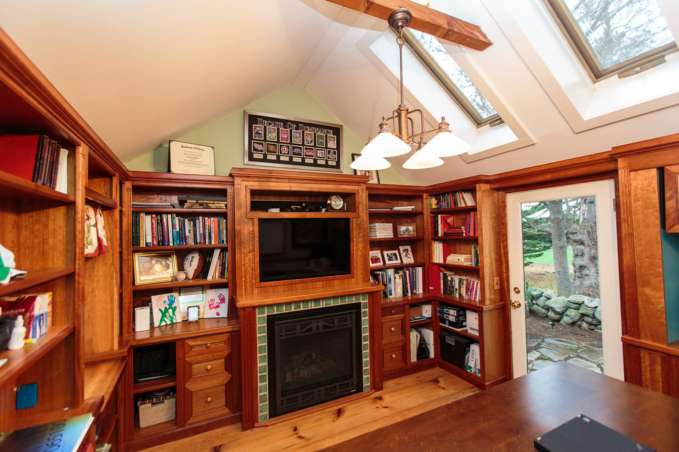 Diseño de sala de estar con biblioteca cerrada tradicional grande con suelo de madera en tonos medios, todas las chimeneas, marco de chimenea de baldosas y/o azulejos y televisor colgado en la pared