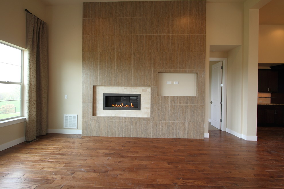 Ejemplo de sala de estar abierta actual de tamaño medio con paredes beige, suelo de madera oscura, chimenea lineal, marco de chimenea de piedra y televisor colgado en la pared