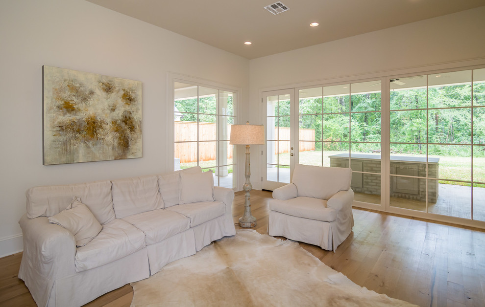Imagen de sala de estar abierta de estilo de casa de campo con suelo de madera clara y televisor colgado en la pared