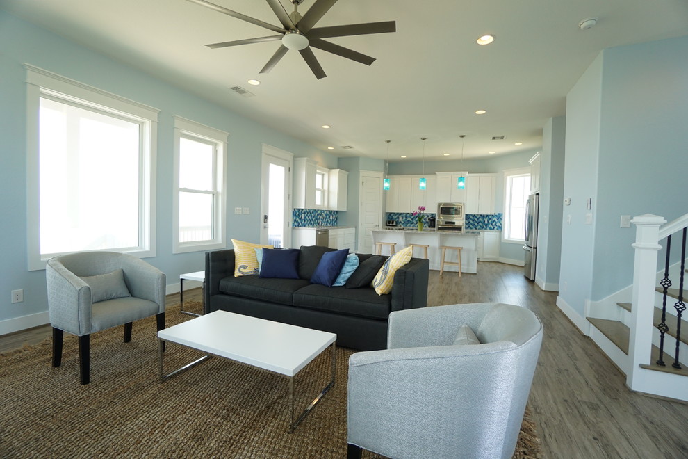 Mittelgroßes, Offenes Modernes Wohnzimmer ohne Kamin mit blauer Wandfarbe, braunem Holzboden und TV-Wand in Houston