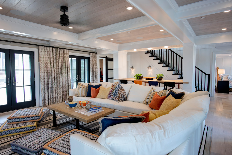 Diseño de sala de estar abierta costera con paredes beige, suelo de madera clara y suelo beige