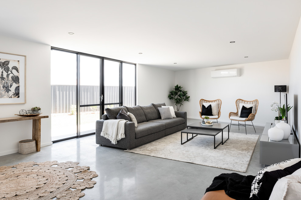 Skandinavisches Wohnzimmer mit weißer Wandfarbe, Betonboden, freistehendem TV und grauem Boden in Perth