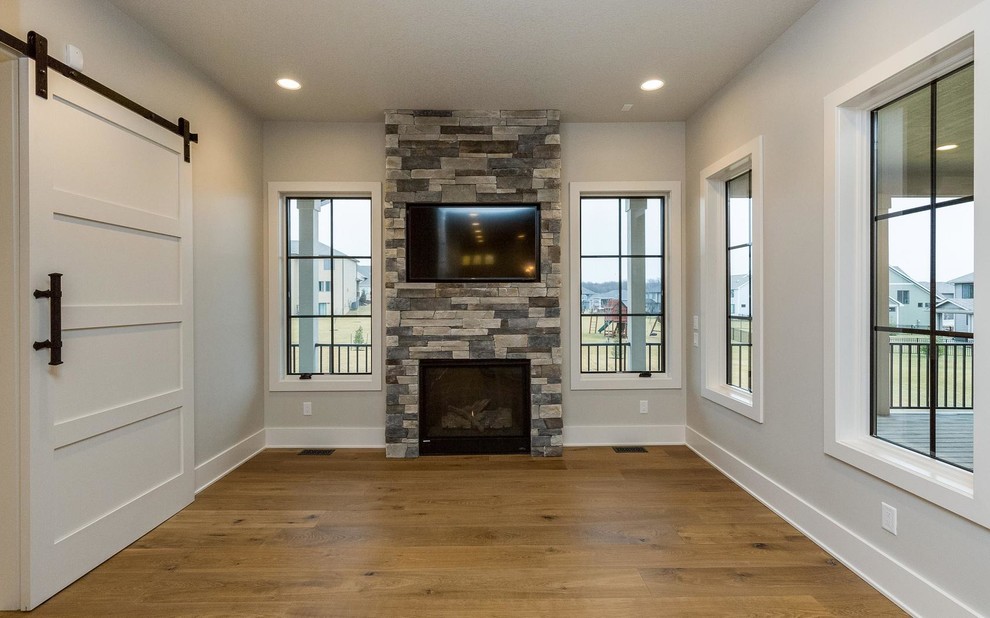 Small traditional enclosed games room in Other with grey walls, light hardwood flooring, a standard fireplace, a stone fireplace surround and a wall mounted tv.