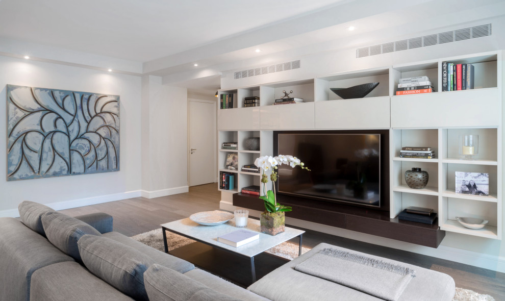 Cette photo montre une grande salle de séjour tendance ouverte avec un mur beige, parquet foncé, un téléviseur encastré et un sol gris.