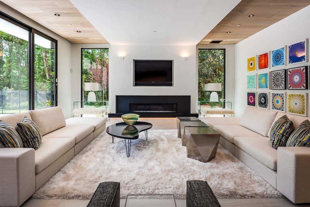 Cette image montre une salle de séjour design avec un mur blanc, un téléviseur encastré, une cheminée ribbon et un sol beige.