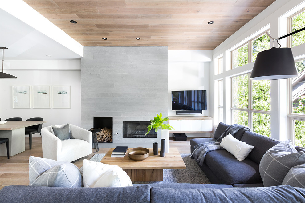 Diseño de salón abierto contemporáneo con paredes blancas, suelo de madera clara, todas las chimeneas y televisor colgado en la pared