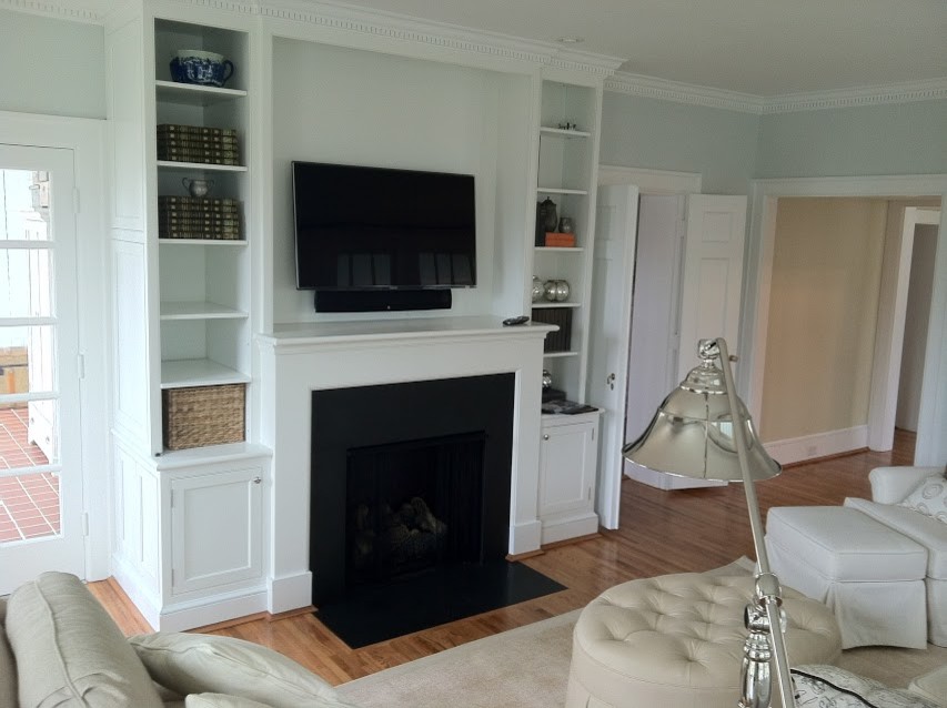 This is an example of a medium sized traditional open plan games room in Other with blue walls, medium hardwood flooring, a standard fireplace, a wooden fireplace surround and a built-in media unit.