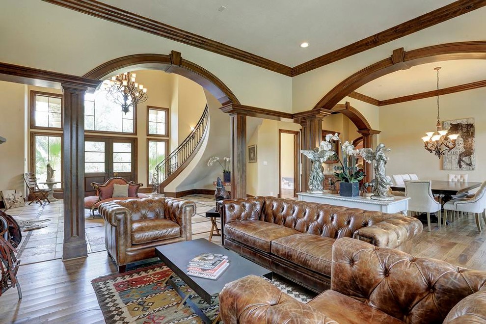 This is an example of a large mediterranean open plan games room in Houston with beige walls, no fireplace, no tv, brown floors and medium hardwood flooring.