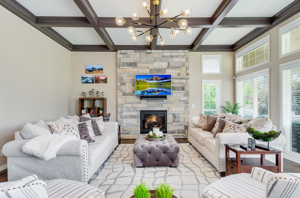 Foto de sala de estar tradicional con paredes beige, suelo de madera oscura, estufa de leña, marco de chimenea de piedra, televisor colgado en la pared y alfombra