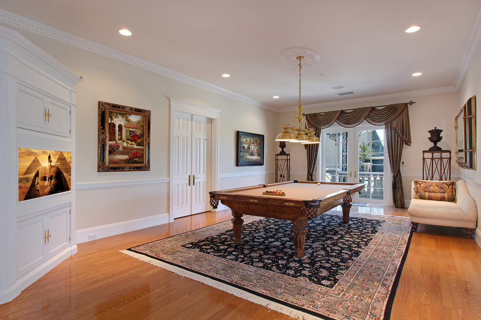Example of a tuscan enclosed medium tone wood floor game room design in Orange County with beige walls
