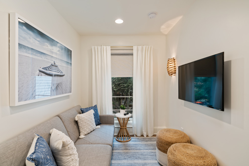 Imagen de sala de estar abierta costera de tamaño medio con paredes blancas, suelo de madera en tonos medios, chimenea de doble cara, marco de chimenea de yeso y suelo gris