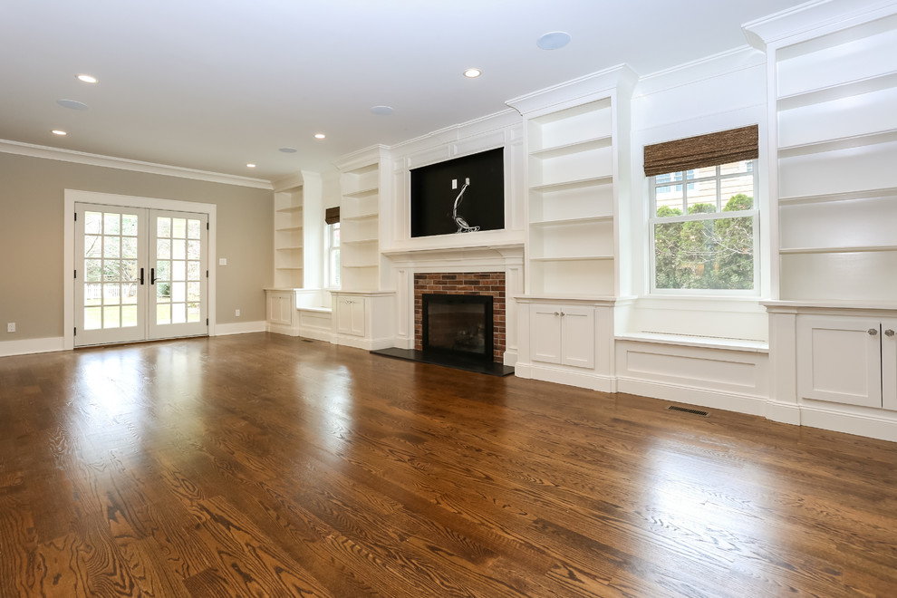 Photo of a large traditional open plan games room in New York with a reading nook, beige walls, medium hardwood flooring, a standard fireplace, a brick fireplace surround and a built-in media unit.