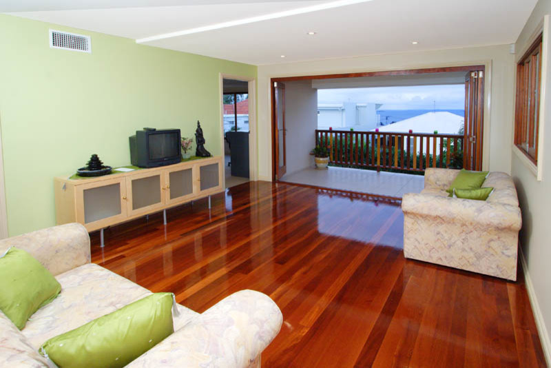 Mittelgroßes, Offenes Asiatisches Wohnzimmer mit bunten Wänden, hellem Holzboden, freistehendem TV und buntem Boden in Brisbane