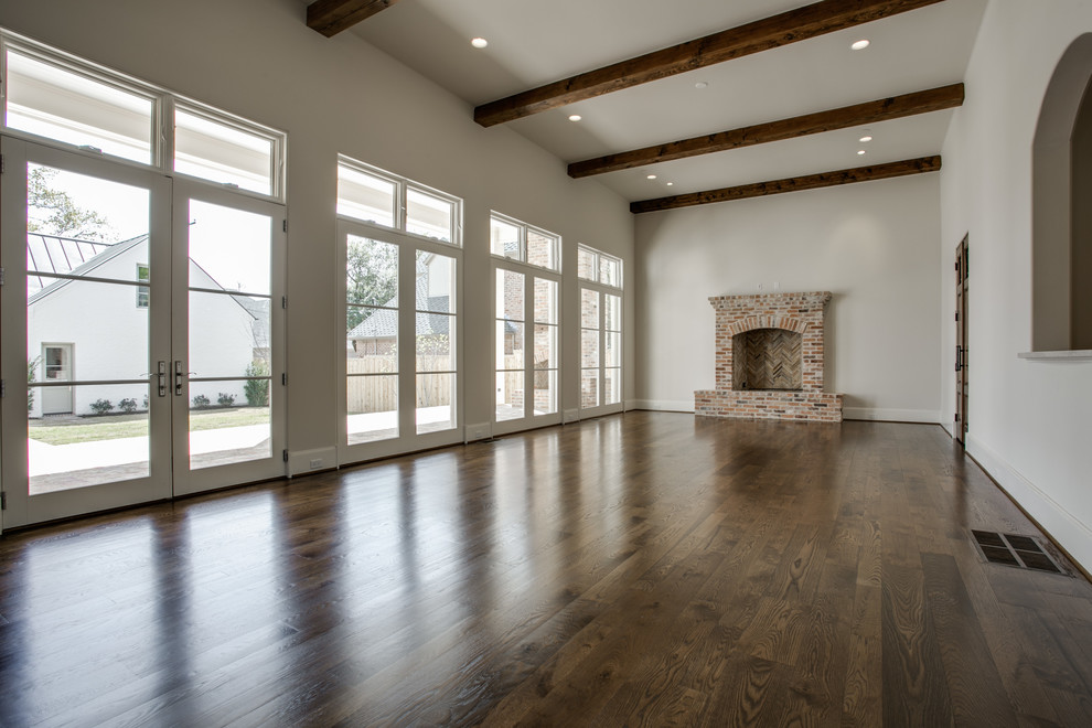 Ejemplo de sala de estar abierta clásica extra grande con suelo de madera en tonos medios, todas las chimeneas, marco de chimenea de ladrillo y televisor colgado en la pared