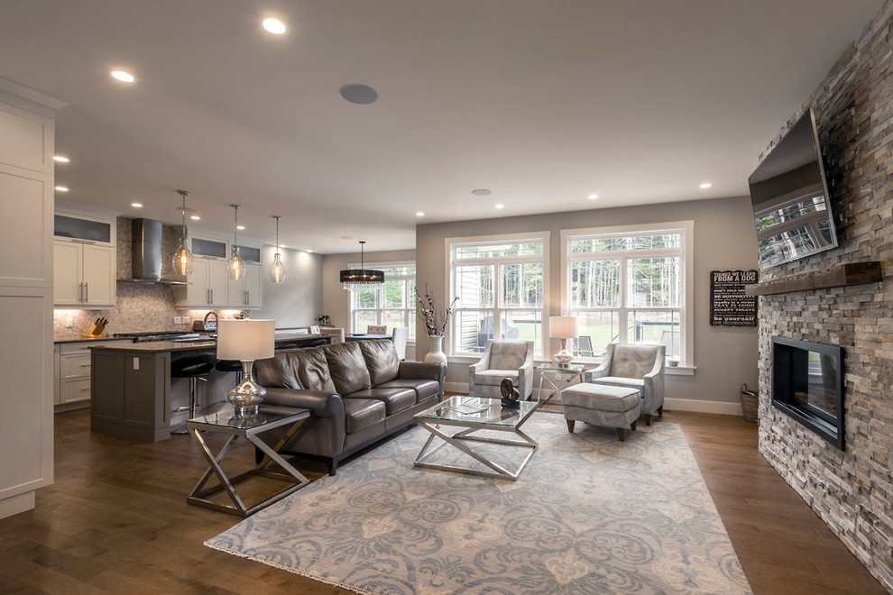Medium sized classic open plan games room in Other with a standard fireplace, a stone fireplace surround, a wall mounted tv, grey walls, medium hardwood flooring and brown floors.
