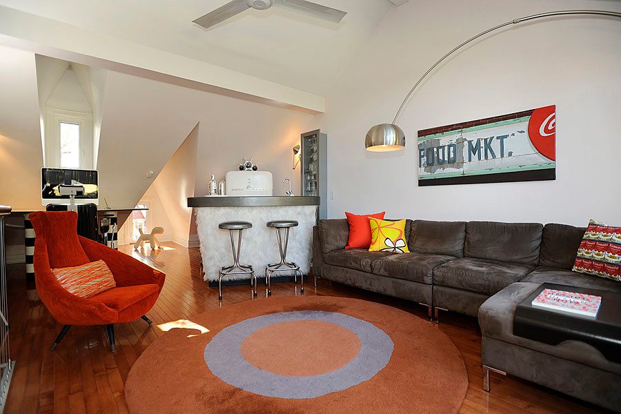 Ejemplo de sala de estar con barra de bar tipo loft ecléctica de tamaño medio con paredes blancas, suelo de madera en tonos medios y televisor colgado en la pared