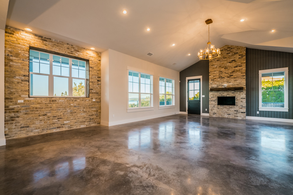 Landhaus Wohnzimmer mit beiger Wandfarbe, Betonboden, Kamin und Kaminumrandung aus Backstein in Austin