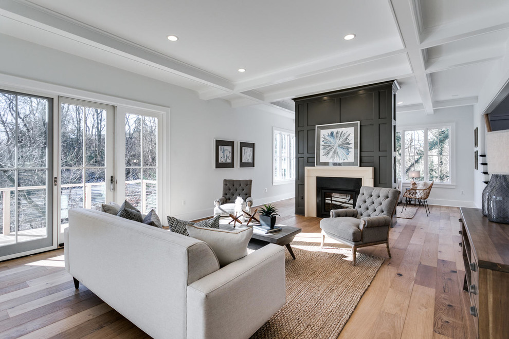 Ejemplo de sala de estar de estilo de casa de campo con suelo de madera clara, chimenea de doble cara y marco de chimenea de piedra