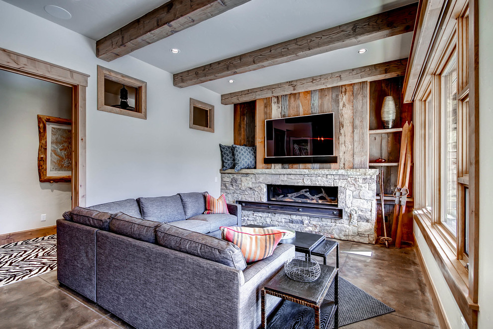 Foto de sala de estar rústica con paredes blancas, suelo de cemento, chimenea lineal, marco de chimenea de piedra y televisor colgado en la pared