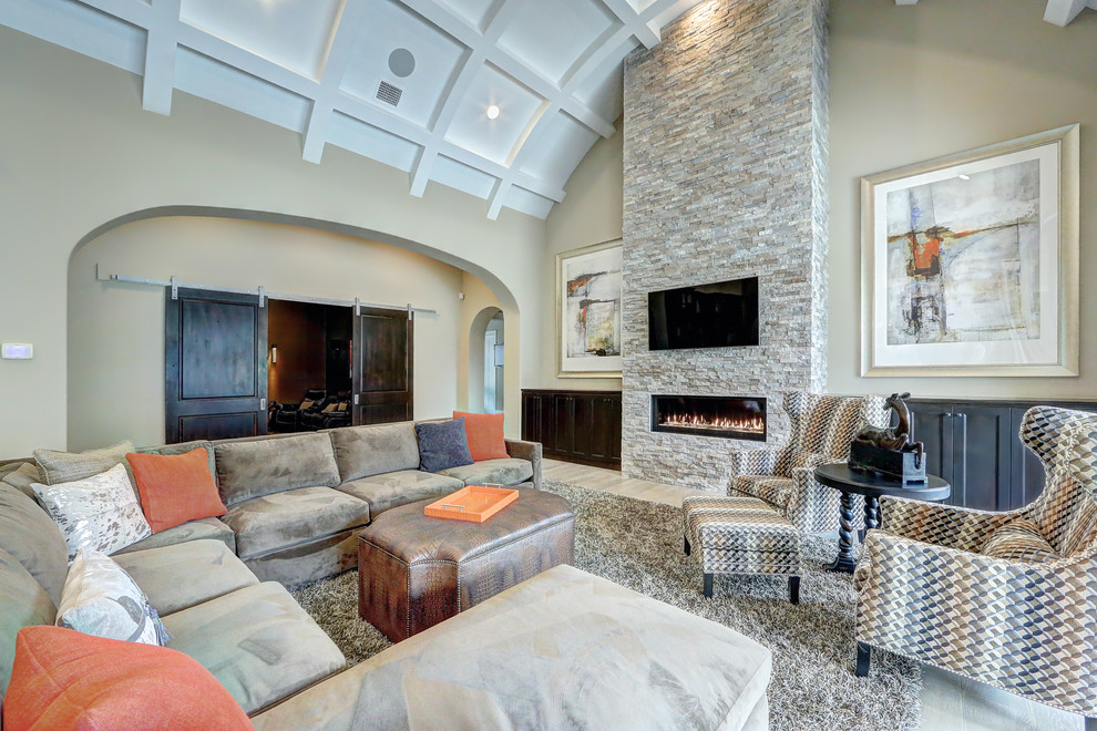 Photo of a large traditional open plan games room in Austin with light hardwood flooring, a stone fireplace surround, a wall mounted tv, beige walls, a ribbon fireplace and beige floors.