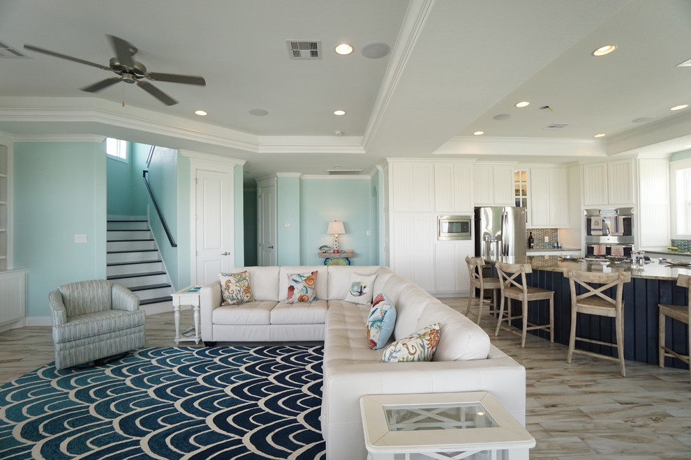 Immagine di un soggiorno stile marino aperto e di medie dimensioni con pareti blu, pavimento in gres porcellanato, nessun camino e TV a parete