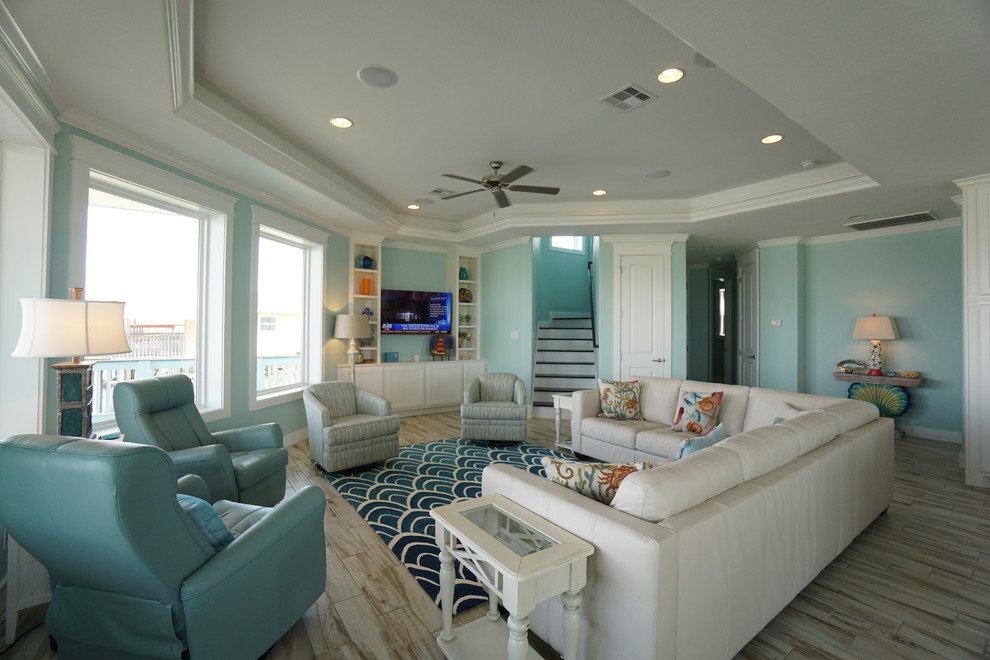 Esempio di un soggiorno stile marinaro aperto e di medie dimensioni con pareti blu, pavimento in gres porcellanato, nessun camino e TV a parete