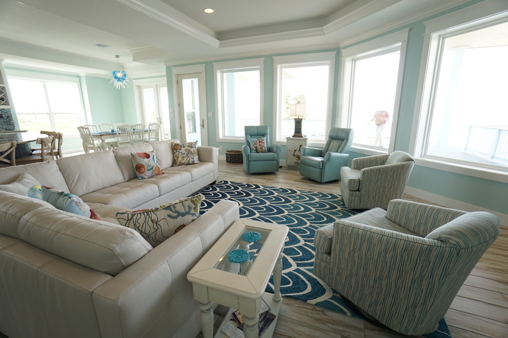 На фото: открытая гостиная комната среднего размера в морском стиле с синими стенами, полом из керамогранита и телевизором на стене без камина с