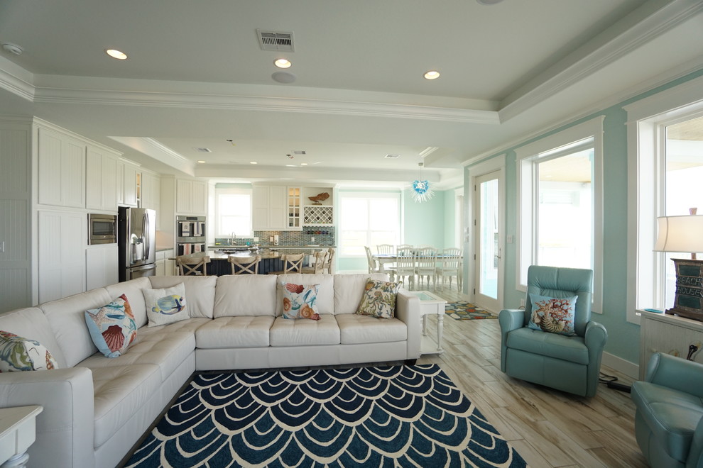 Immagine di un soggiorno stile marinaro aperto e di medie dimensioni con pareti blu, pavimento in gres porcellanato, nessun camino e TV a parete
