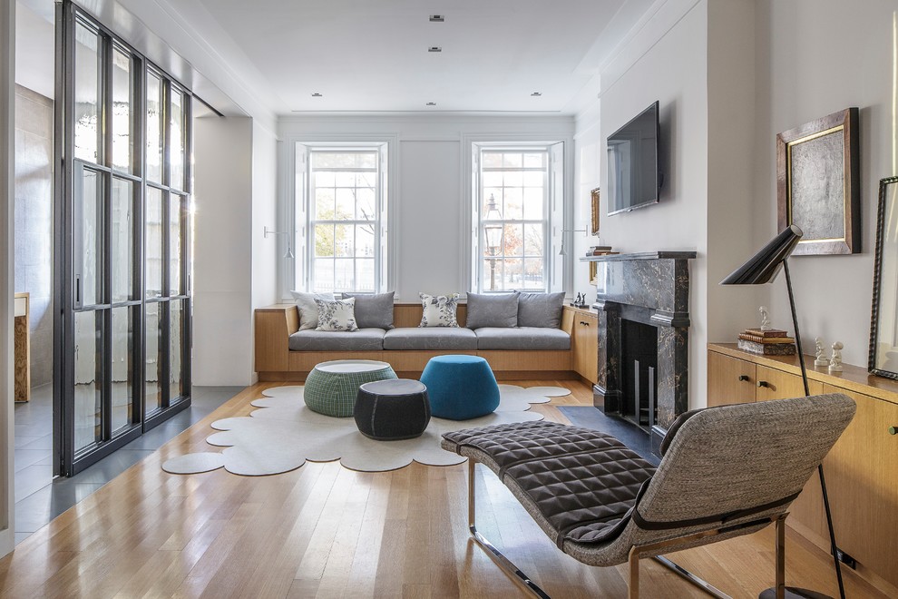 Diseño de sala de estar contemporánea con paredes beige, suelo de madera clara, todas las chimeneas, televisor colgado en la pared y suelo beige