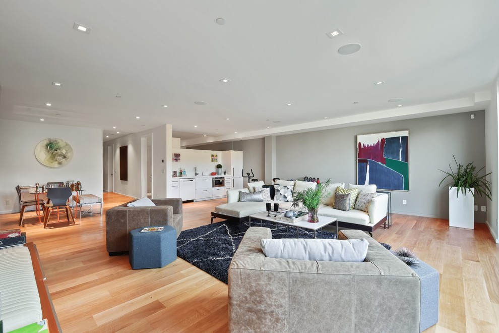 This is an example of a contemporary open plan living room in San Francisco with grey walls, medium hardwood flooring and brown floors.