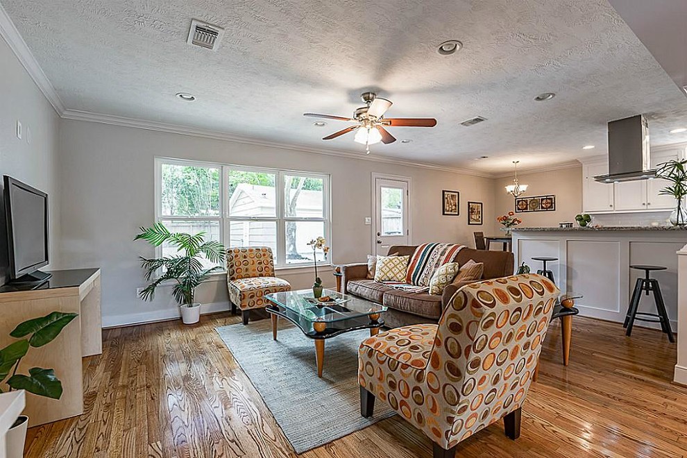 Mittelgroßes, Offenes Rustikales Wohnzimmer ohne Kamin mit grauer Wandfarbe, braunem Holzboden, freistehendem TV und braunem Boden in Houston