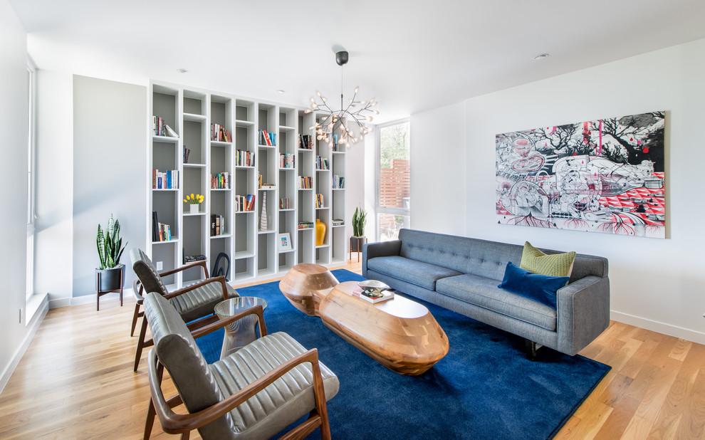 Ejemplo de sala de estar con biblioteca cerrada actual con paredes blancas, suelo de madera en tonos medios y suelo marrón