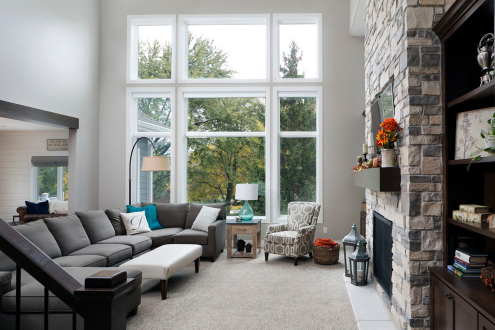 Modelo de sala de estar abierta clásica renovada grande con paredes marrones, moqueta, todas las chimeneas, marco de chimenea de piedra y televisor colgado en la pared